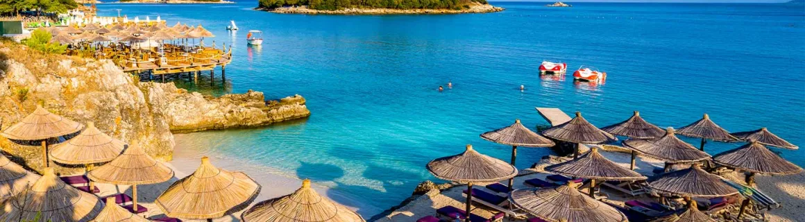 Sandstrand mit Sonnenschirmen und Liegestühlen in Ksamil  