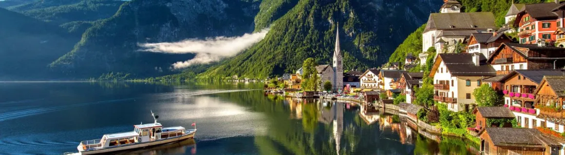 Village en Autriche au bord du lac avec un bateau qui vogue